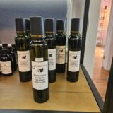 Rosemary Garlic Infused Olive Oil bottle by a white picket fence